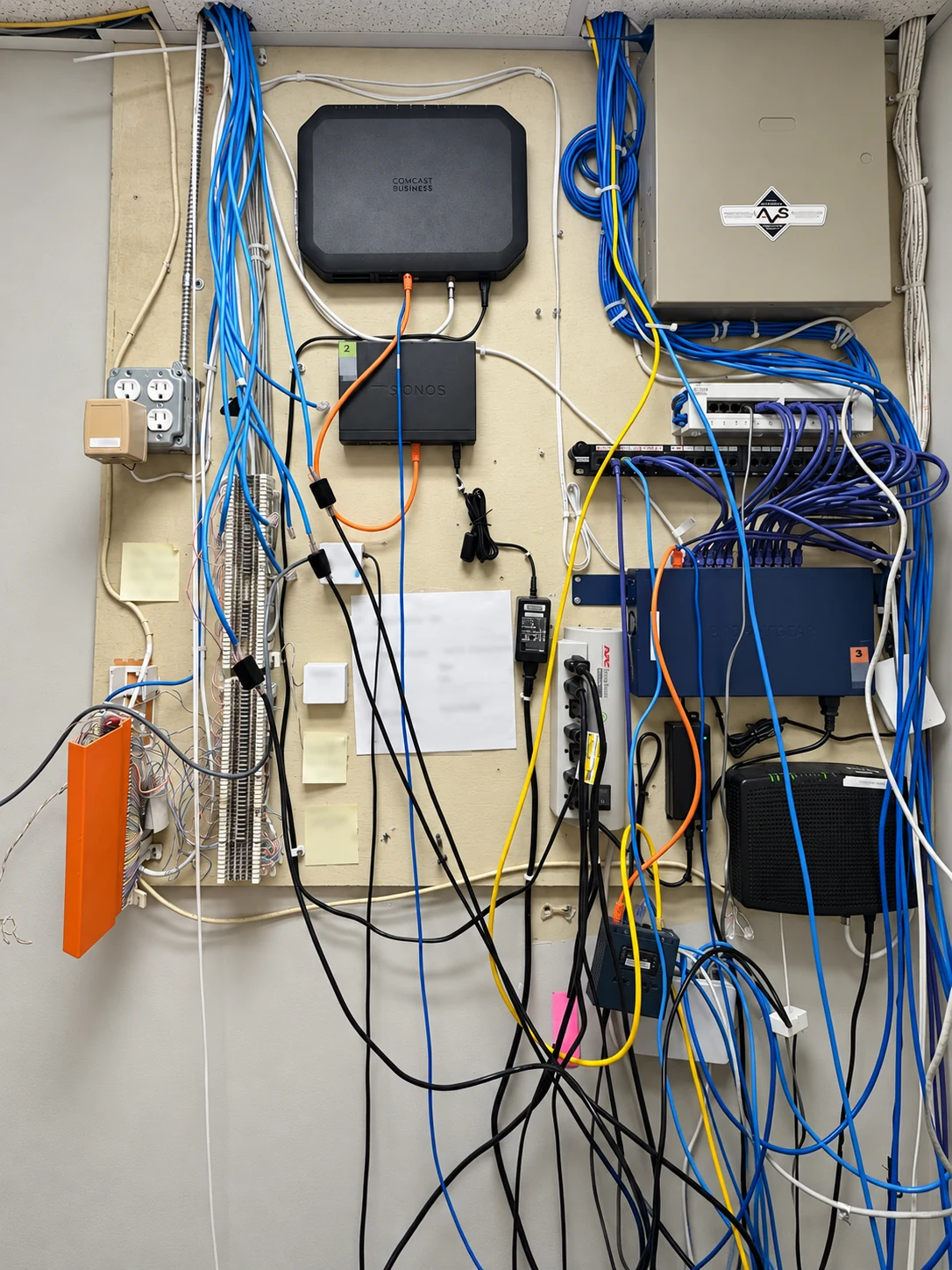 Before: wall-mounted network equipment with loose cable runs and hanging connections.